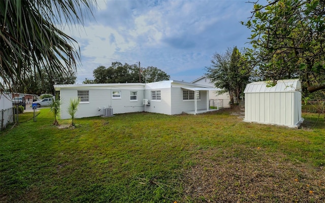 rear view of house with central AC, a storage unit, and a lawn