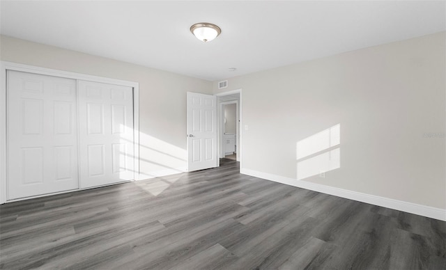 unfurnished bedroom featuring dark hardwood / wood-style flooring and a closet