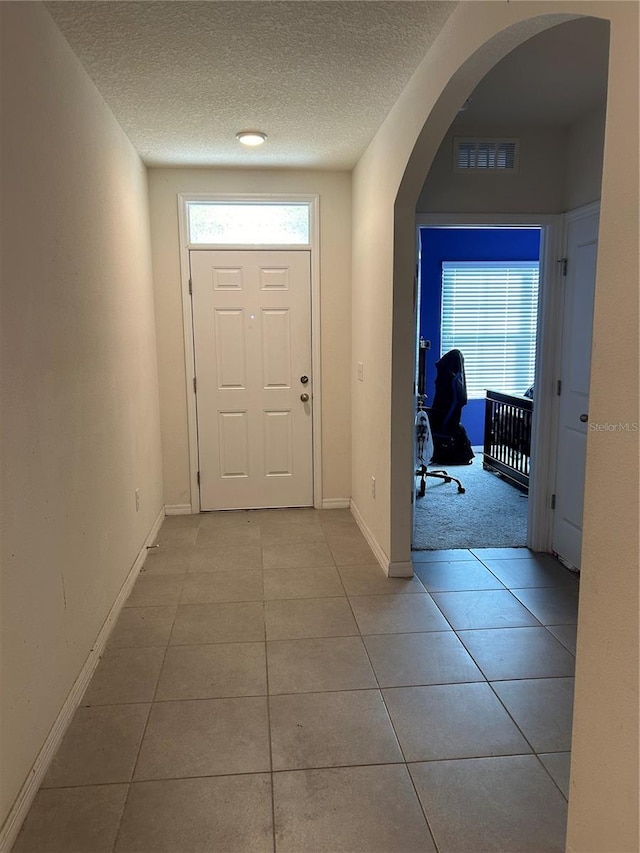 entryway featuring light tile patterned floors and a textured ceiling