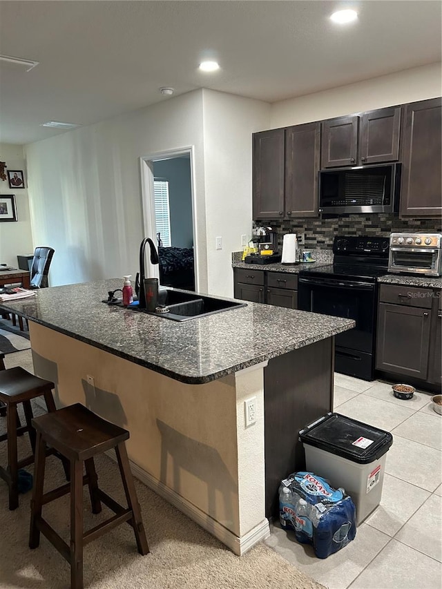 kitchen with a kitchen breakfast bar, a center island with sink, black / electric stove, and sink