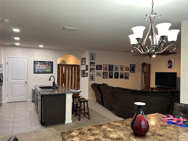 kitchen with light carpet, sink, pendant lighting, a center island with sink, and an inviting chandelier