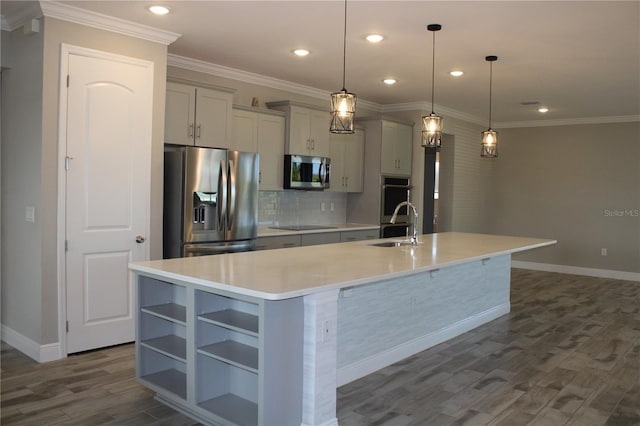 kitchen with appliances with stainless steel finishes, decorative light fixtures, sink, and a center island with sink