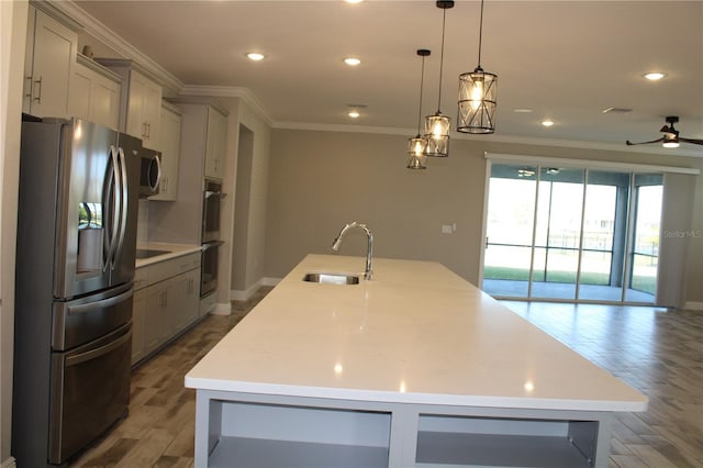 kitchen with appliances with stainless steel finishes, hanging light fixtures, a large island with sink, ceiling fan, and sink