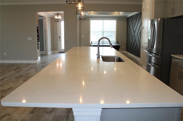 kitchen featuring sink, light hardwood / wood-style floors, hanging light fixtures, stainless steel fridge with ice dispenser, and a center island with sink