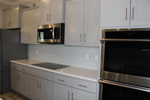 kitchen with appliances with stainless steel finishes, ornamental molding, dark hardwood / wood-style flooring, and decorative backsplash