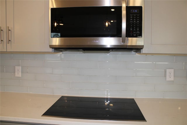 room details with black electric cooktop and backsplash