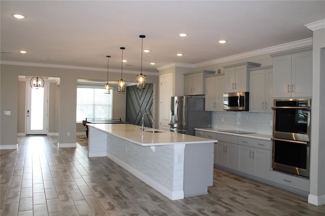 kitchen featuring sink, decorative light fixtures, an island with sink, gray cabinetry, and appliances with stainless steel finishes