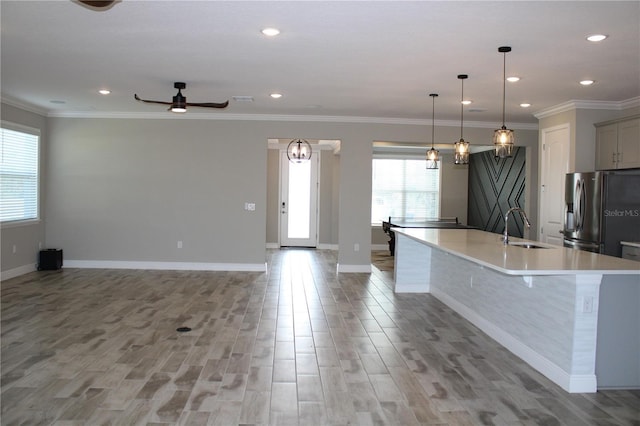 kitchen with gray cabinets, a large island with sink, stainless steel fridge, sink, and decorative light fixtures