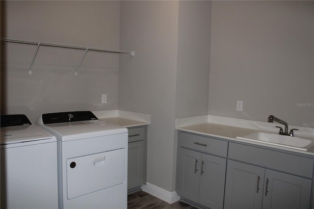 laundry room with washing machine and dryer, cabinets, dark hardwood / wood-style flooring, and sink