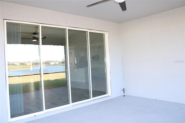 doorway to property with a patio area, ceiling fan, and a water view