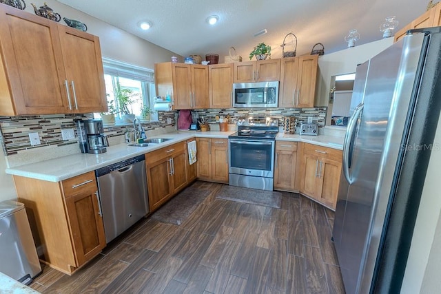 kitchen with vaulted ceiling, appliances with stainless steel finishes, sink, and decorative backsplash