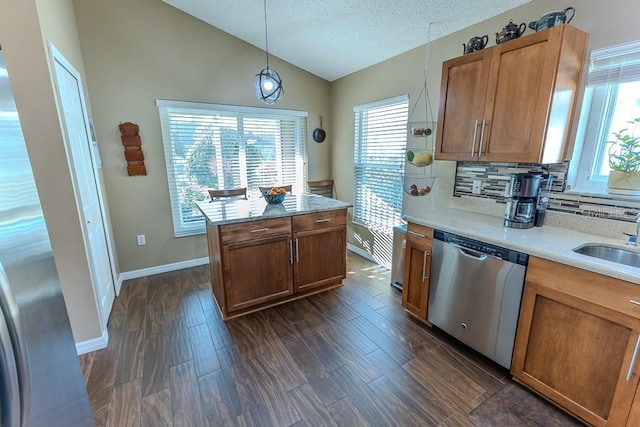 kitchen featuring lofted ceiling, sink, hanging light fixtures, dark hardwood / wood-style flooring, and stainless steel dishwasher