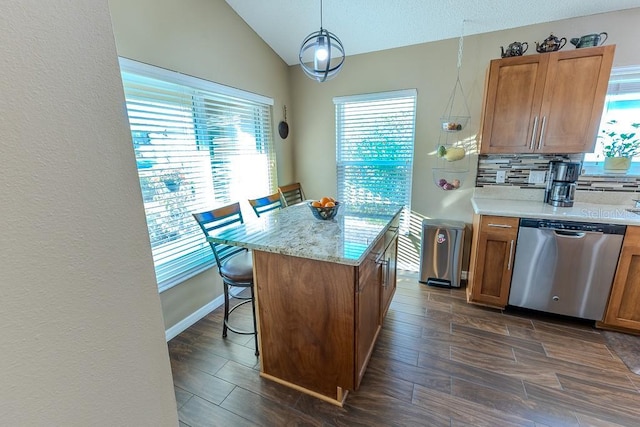 kitchen with a kitchen bar, decorative light fixtures, vaulted ceiling, stainless steel dishwasher, and decorative backsplash