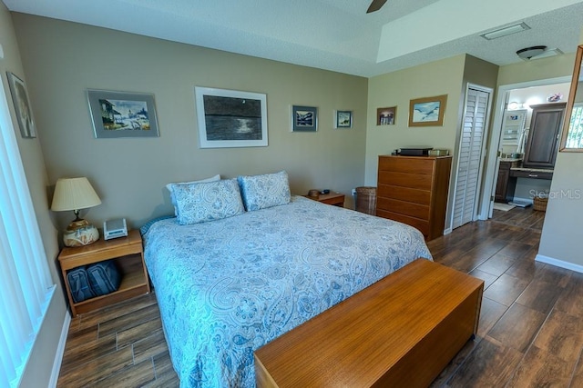 bedroom featuring ceiling fan, dark hardwood / wood-style floors, ensuite bath, and a closet