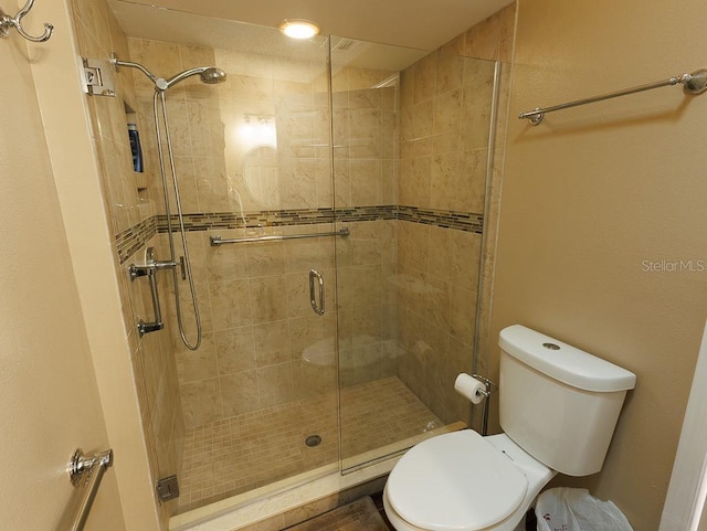 bathroom featuring a shower with shower door and toilet