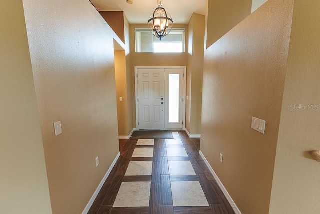 1604 Boswell Ln, New Port Richey, FL 34655 - foyer featuring baseboards, a chandelier, dark wood-style flooring, inlaid floor details, and a high ceiling