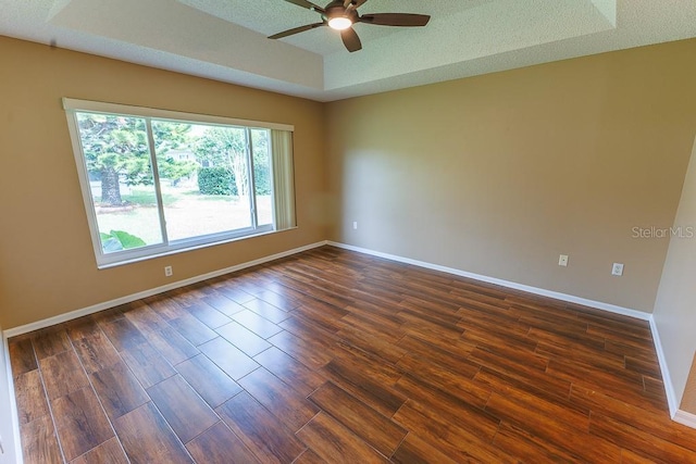 1604 Boswell Ln, New Port Richey, FL 34655 - spare room featuring a ceiling fan, dark wood-type flooring, baseboards, and a tray ceiling