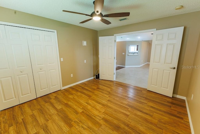 1604 Boswell Ln, New Port Richey, FL 34655 - unfurnished bedroom featuring light wood-style flooring, baseboards, a closet, a ceiling fan, and a textured ceiling