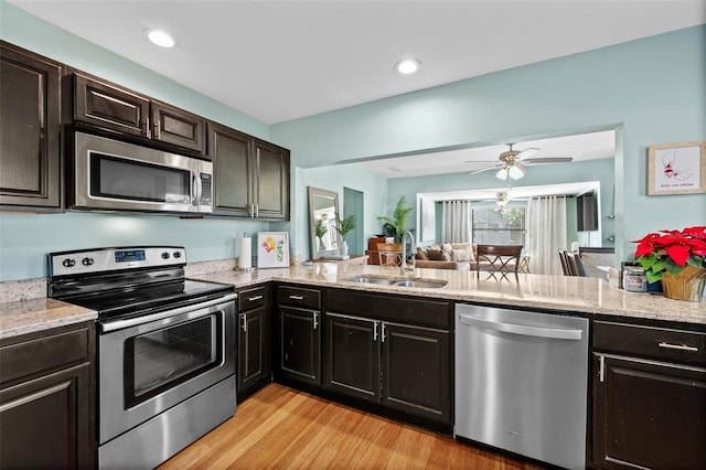 kitchen featuring stainless steel appliances, sink, light stone counters, light hardwood / wood-style floors, and dark brown cabinetry