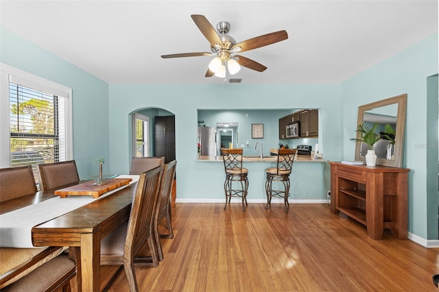 dining area featuring sink, light wood-type flooring, and ceiling fan