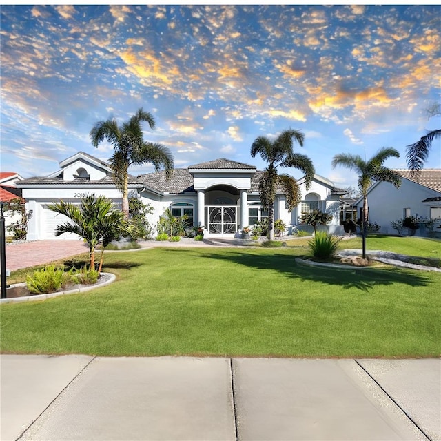 mediterranean / spanish home featuring a garage and a lawn