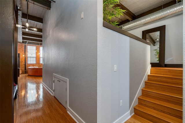 stairway with hardwood / wood-style floors and beamed ceiling