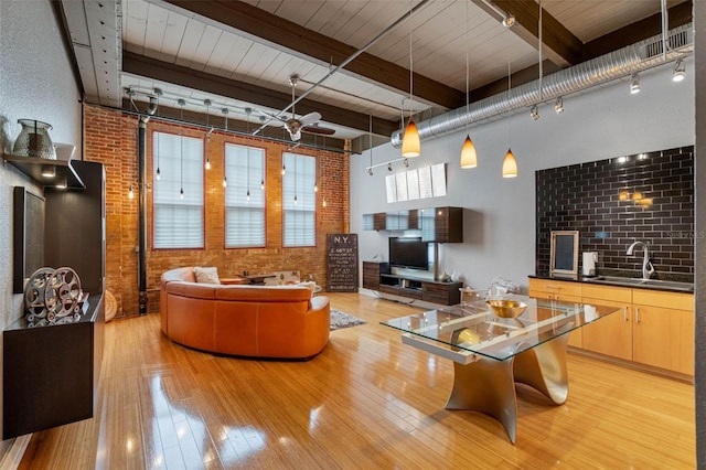 living room with brick wall, beam ceiling, ceiling fan, and sink