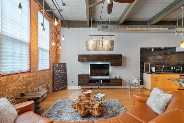 living room featuring light hardwood / wood-style floors, ceiling fan, a wealth of natural light, and brick wall