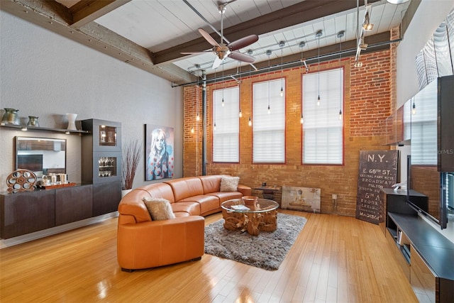 living room featuring brick wall, beam ceiling, ceiling fan, and wood-type flooring