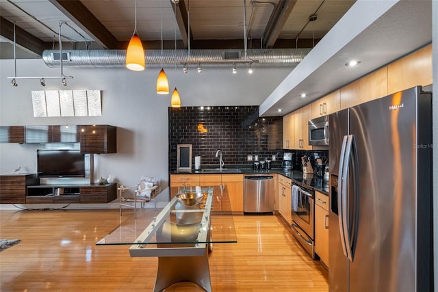 kitchen featuring hanging light fixtures, stainless steel appliances, light brown cabinets, light wood-type flooring, and sink