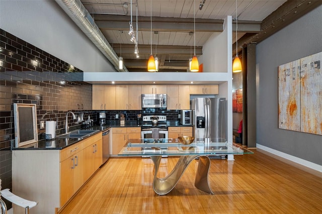 kitchen featuring appliances with stainless steel finishes, pendant lighting, light brown cabinetry, sink, and backsplash