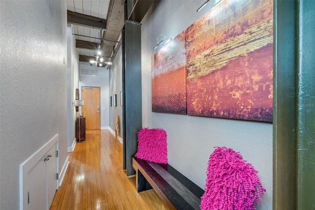 corridor with a towering ceiling and light hardwood / wood-style flooring