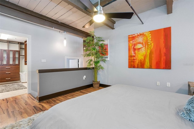 bedroom with beam ceiling, ceiling fan, a spacious closet, and hardwood / wood-style floors