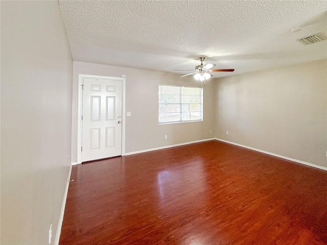 unfurnished room with ceiling fan, a textured ceiling, and dark hardwood / wood-style floors