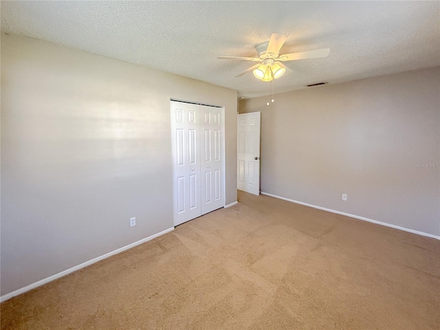 unfurnished bedroom with light carpet, a closet, ceiling fan, and a textured ceiling