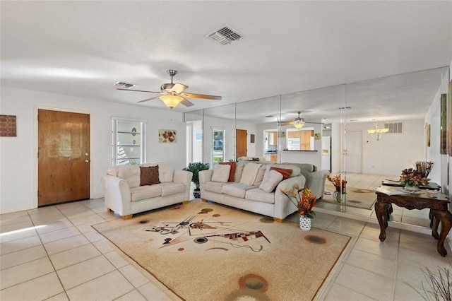 living room with light tile patterned flooring and ceiling fan with notable chandelier