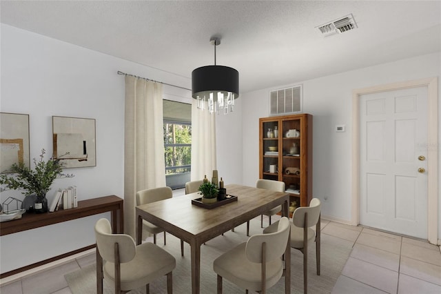 tiled dining room featuring a notable chandelier and a textured ceiling