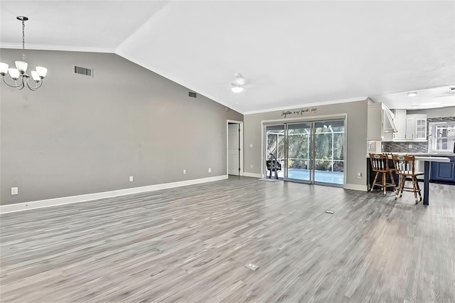 unfurnished living room featuring vaulted ceiling, crown molding, ceiling fan with notable chandelier, and light hardwood / wood-style flooring