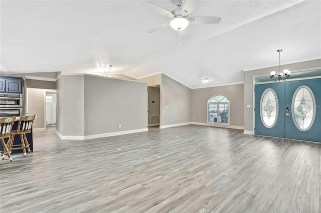 unfurnished living room with lofted ceiling, light wood-type flooring, crown molding, and ceiling fan with notable chandelier