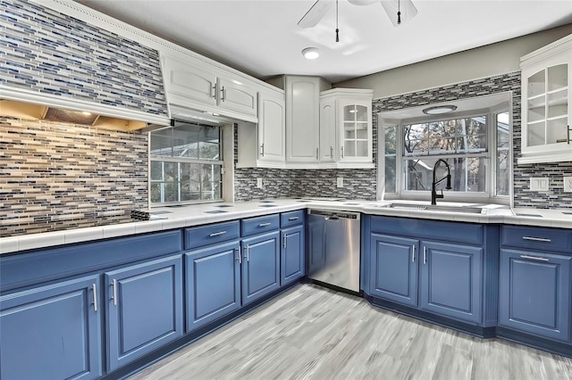 kitchen featuring exhaust hood, blue cabinetry, dishwasher, white cabinets, and sink