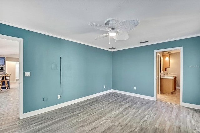 unfurnished bedroom with ceiling fan, crown molding, ensuite bath, and light wood-type flooring