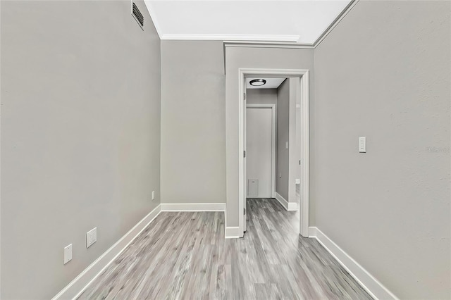 hall with light wood-type flooring and ornamental molding