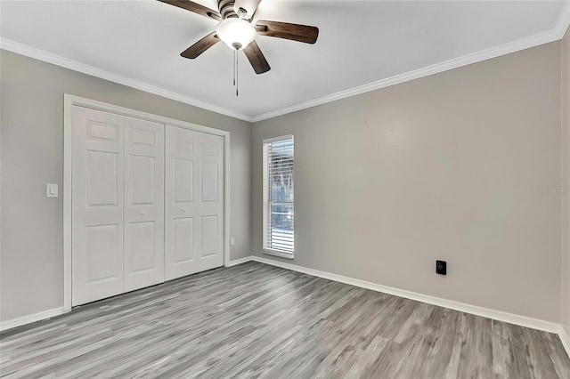 unfurnished bedroom featuring ceiling fan, a closet, light hardwood / wood-style flooring, and crown molding