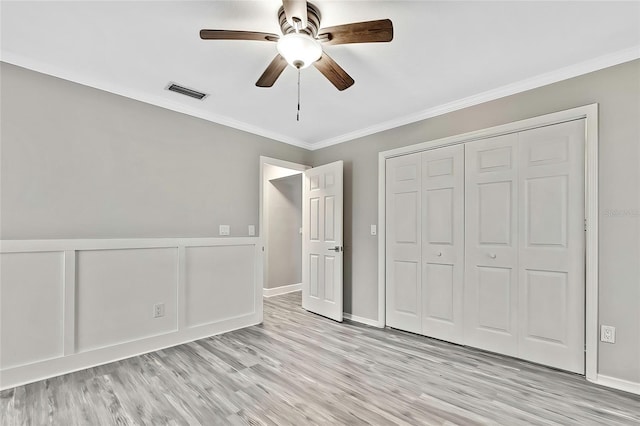 unfurnished bedroom with ceiling fan, a closet, crown molding, and light hardwood / wood-style flooring