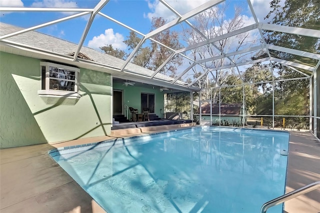 view of swimming pool featuring ceiling fan, glass enclosure, and a patio