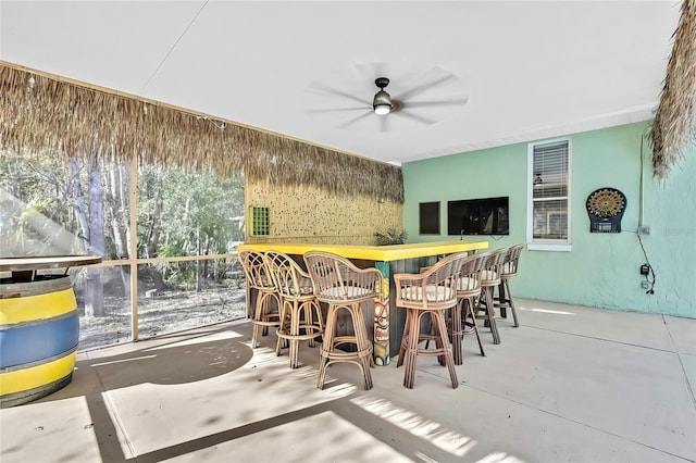 interior space with ceiling fan, indoor bar, and concrete flooring