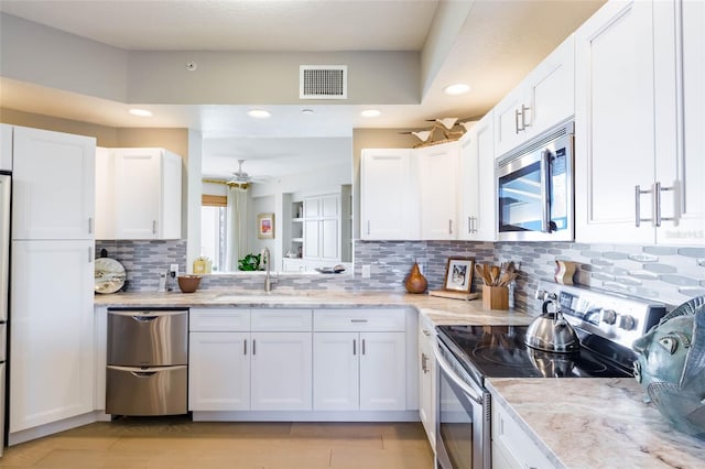 kitchen with stainless steel appliances, white cabinetry, tasteful backsplash, and sink