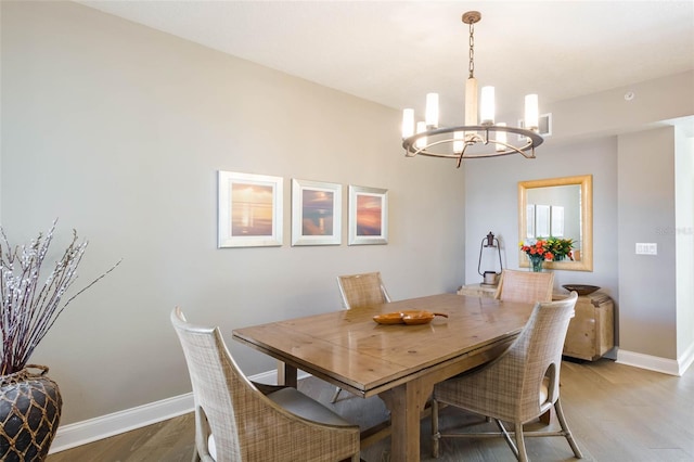 dining space with hardwood / wood-style floors and an inviting chandelier