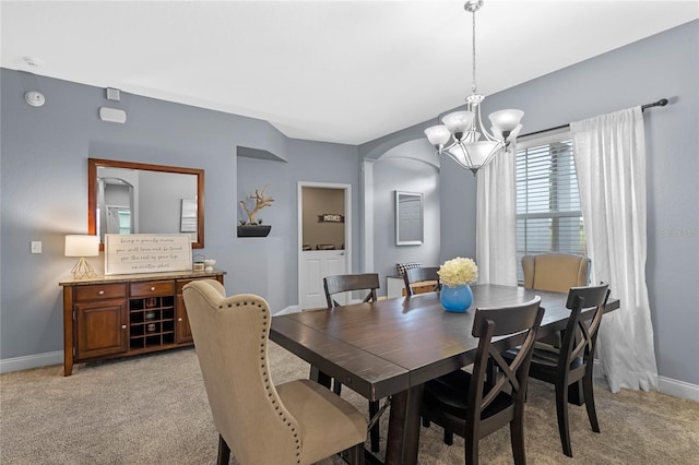 carpeted dining space with an inviting chandelier