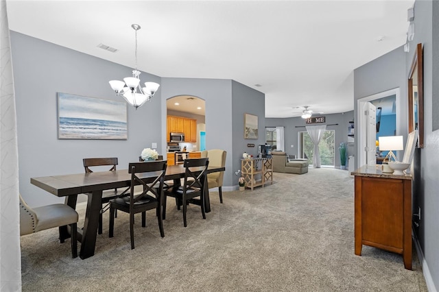 dining space featuring ceiling fan with notable chandelier and light carpet